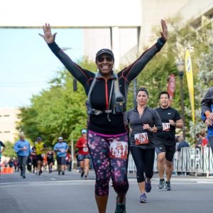 Photo of woman with hands in the air, crossing finish line of a half marathon. 